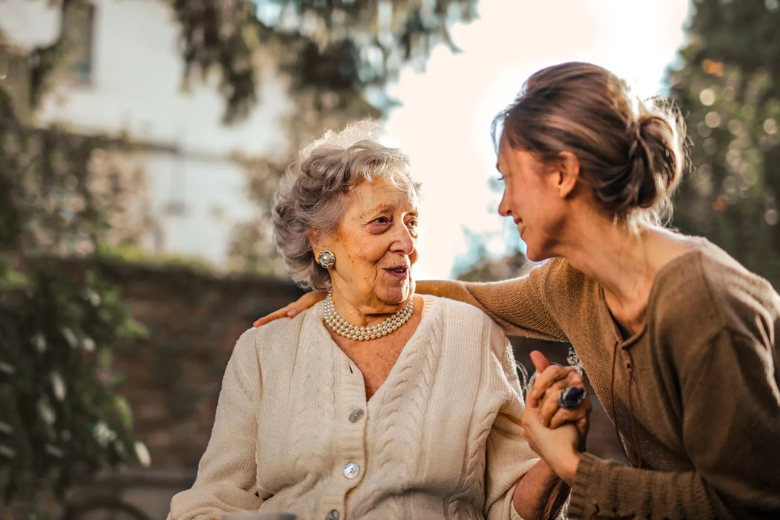 An adult daughter greeting her smiling mother outdoors