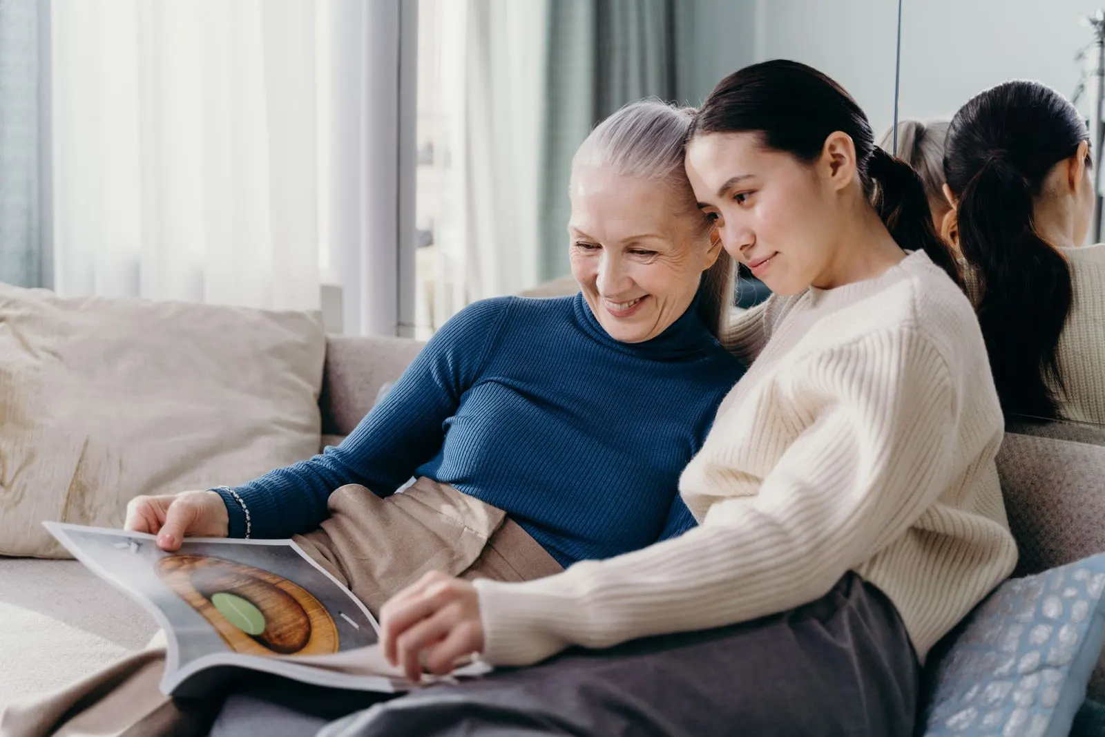 A mother and her adult daughter relaxing together on the couch at home